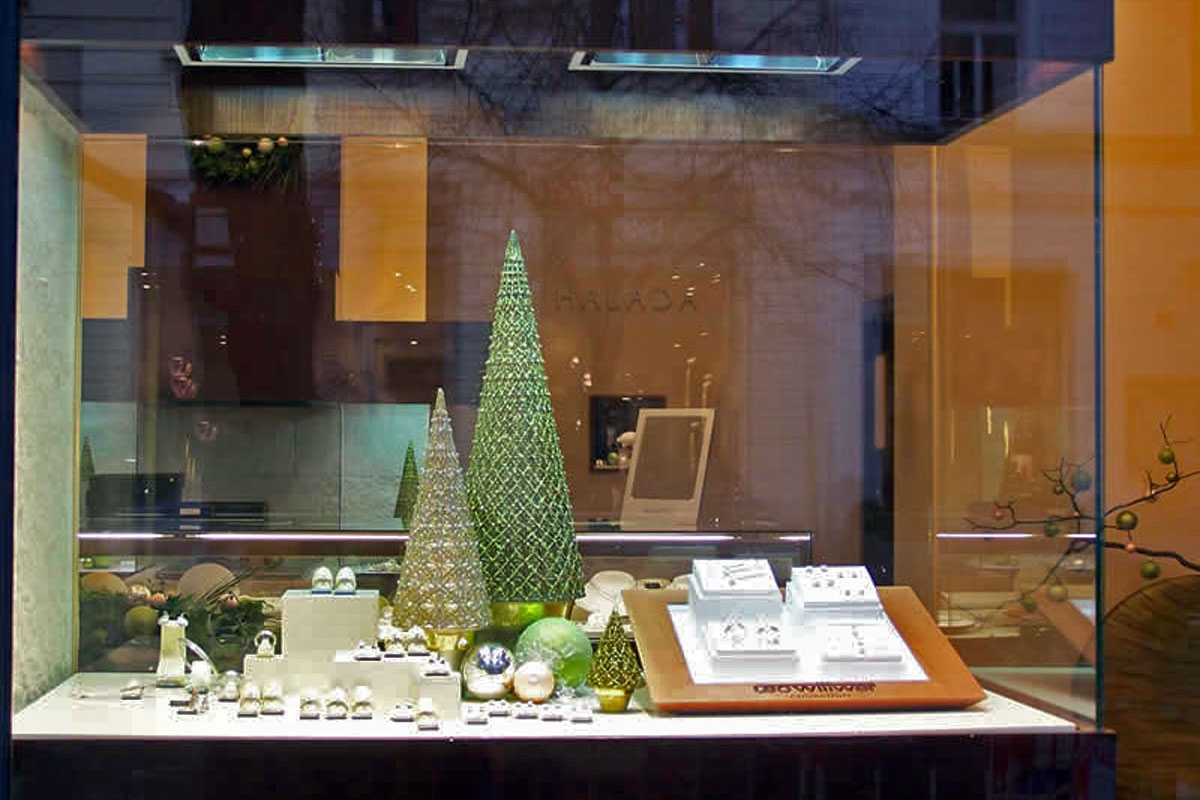 Vánoční dekorativní stromečky a ozdoby ve vitríně s naaranžovanými šperky