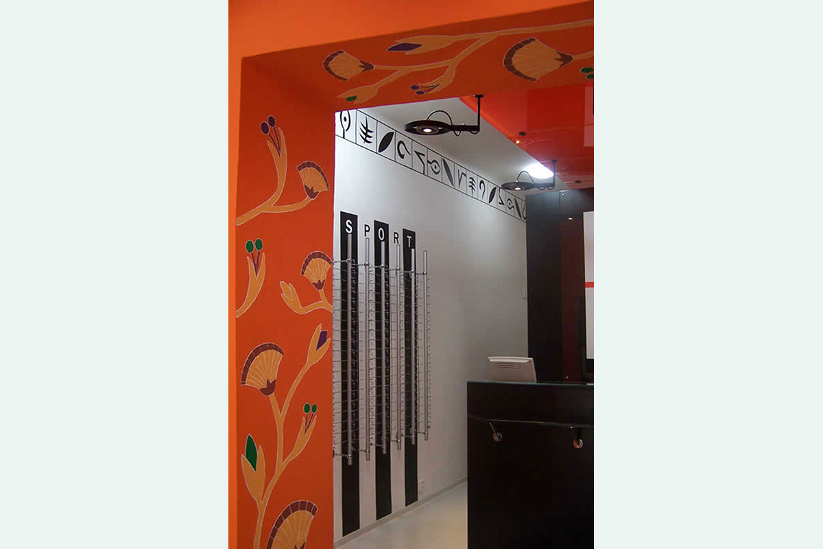 Prodejna Horus a malba v interiéru, oranžové stěny s květy, bílá s černými symboly