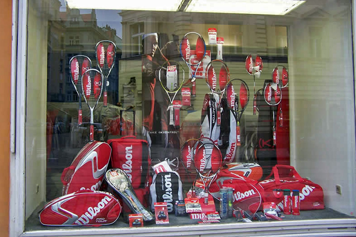 Prodejna sportovních potřeb část pro tenis, naaranžovaná výloha s nabídkou vybavení pro tenisty