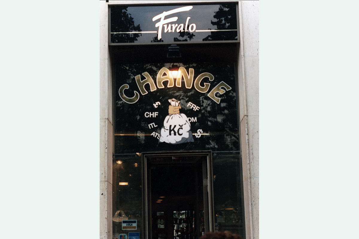 Na vstupu do prodejny nápis Change zlaté písmo s bílou konturou, měšec černá, bílá a kombinace šedých, řezaná reklama